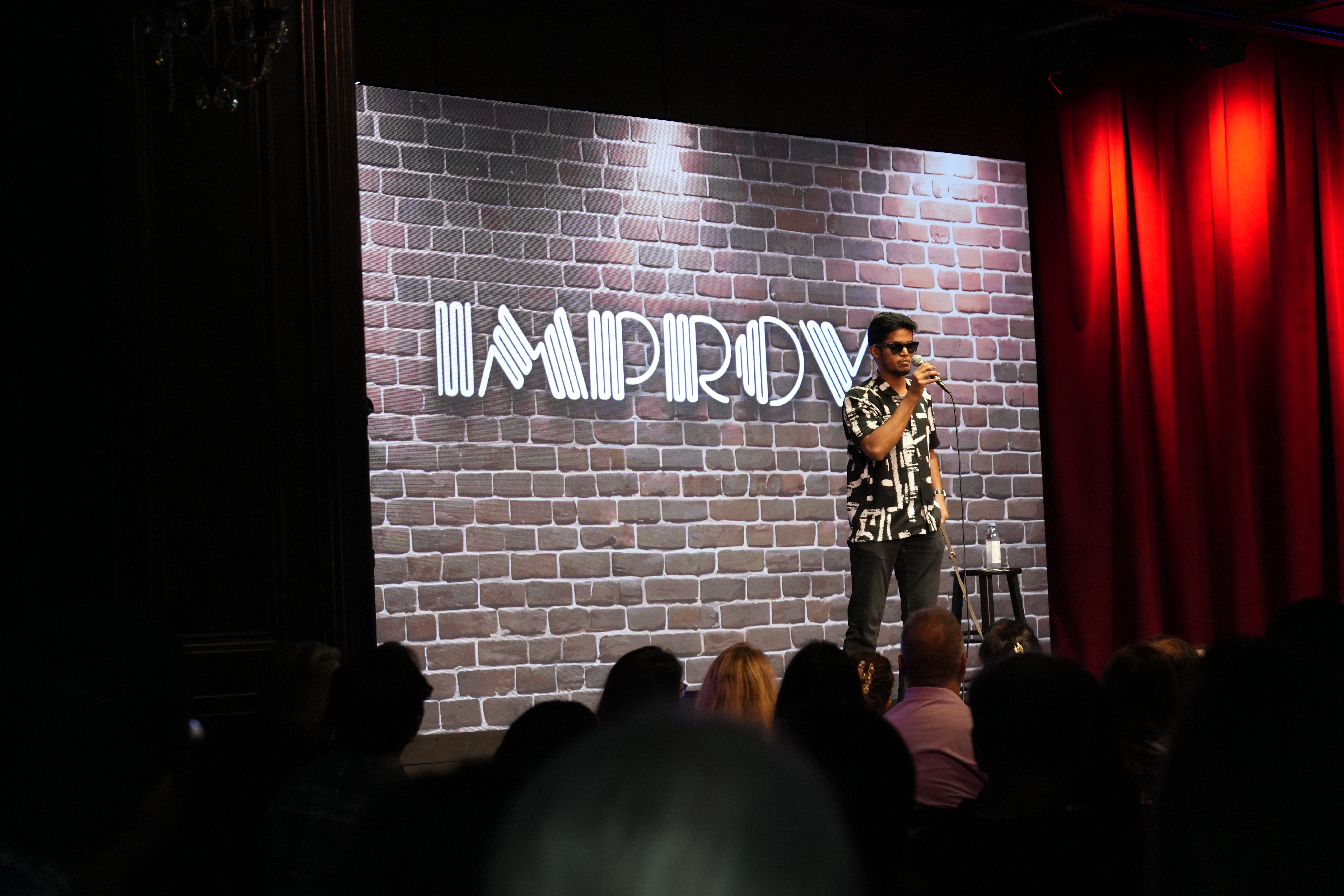 Bhavya performs on an Improv-club stage to a packed audience